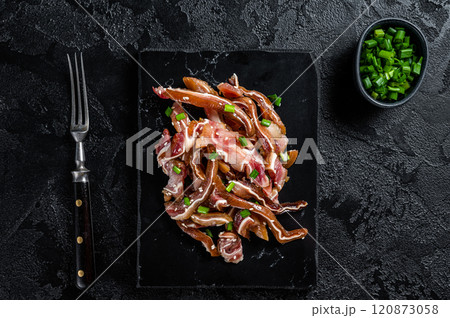 Fried pig ears with sesame seeds and green onions. Fried pork ears in korean style with spicy sauce. Black background. Top view 120873058