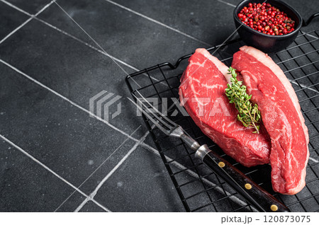 Sirloin steak or Cap Rump, raw beef meat with herbs on a rack. Black background. Top view. Copy space Sirloin steak or Cap Rump, raw beef meat with herbs on a rack. Black background. Top view. Copy space 120873075