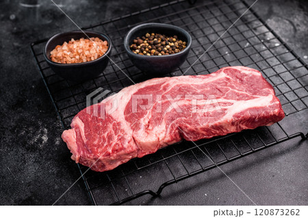 Ready for cooking Chuck eye roll steak, fresh raw beef meat on a rack. black background. top view 120873262