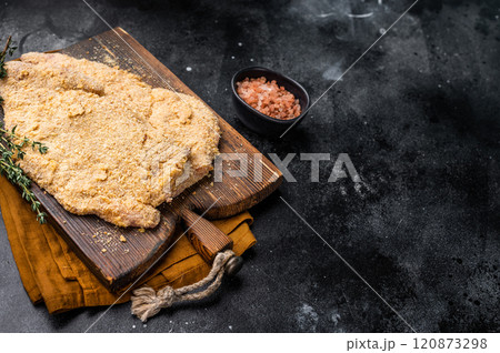 Wiener breaded raw pork Schnitzel, meat steak on a wooden board. black background. top view Wiener breaded raw pork Schnitzel, meat steak on a wooden board. black background. top view 120873298