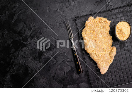 Raw breaded pork Schnitzel steak on a rack. black background. top view 120873302