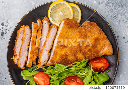 Fried Weiner schnitzel steak, veal breaded meat with salad on a plate. grey background. top view 120873310