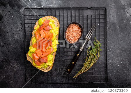 Toast with salty salmon, trout slices, avocado and red caviar. black background. top view Toast with salty salmon, trout slices, avocado and red caviar. black background. top view 120873369
