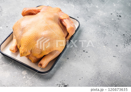 A whole raw chicken sits in a white tray on a grey background A whole raw chicken sits in a white tray on a grey background 120873635