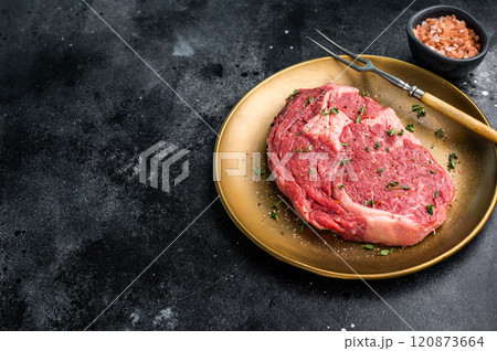 Raw Rib eye steak with herbs and spice in plate, fresh beef meat. black background. top view 120873664