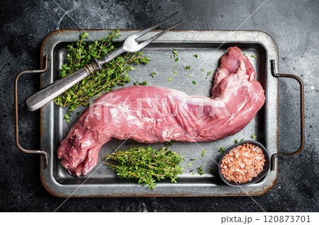 Raw pork tenderloin fillet meat in steel tray with herbs. Black background. Top view Raw pork tenderloin fillet meat in steel tray with herbs. Black background. Top view 120873701