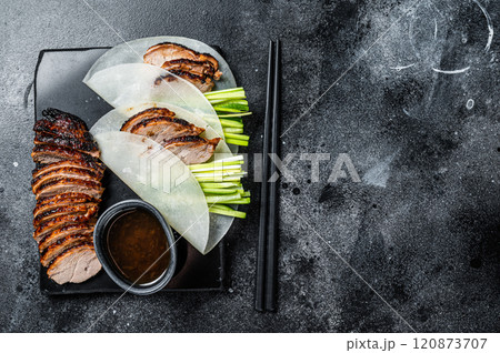 Traditional served Peking Duck with cucumber, green onion, in wheaten chinese pancakes. Black background. Top view. Copy space Traditional served Peking Duck with cucumber, green onion, in wheaten chinese pancakes. Black background. Top view. Copy space 120873707