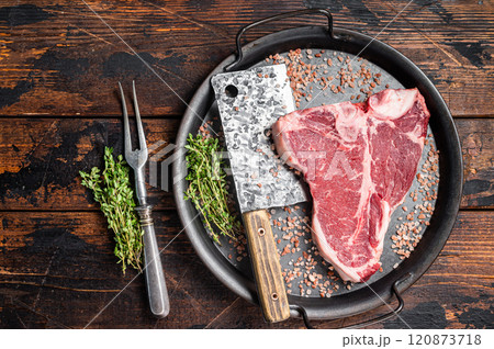 Raw Florentine steak or T bone steak, marbled beef meat in a steel kitchen tray. Wooden background. Top view 120873718