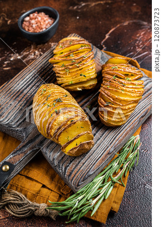 Roasted Hasselback Potato with Fresh thyme and rosemary. Dark background. Top view 120873723