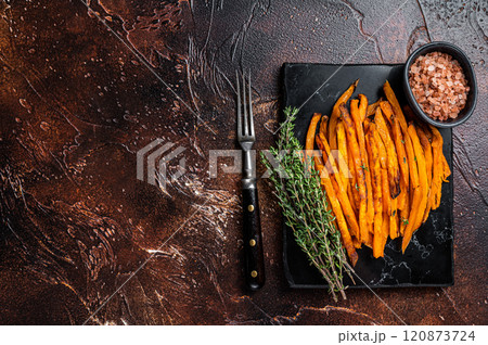 Fried sweet potato french fries on a board with thyme. Dark background. Top view. Copy space Fried sweet potato french fries on a board with thyme. Dark background. Top view. Copy space 120873724