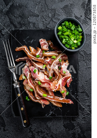 Fried pig ears with sesame seeds and green onions. Fried pork ears in korean style with spicy sauce. Black background. Top view Fried pig ears with sesame seeds and green onions. Fried pork ears in korean style with spicy sauce. Black background. Top view 120873858