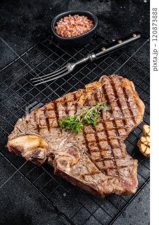 Grilled T-bone or Porterhouse beef meat Steak on a rack. Black background. Top view 120873888