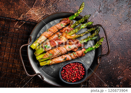 Baked Prosciutto wrapped green asparagus. Dark background. Top view 120873904