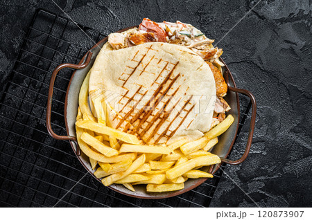 Doner kebab sandwich in grilled pita bread with vegetables and chicken meat. Black background. Top view Doner kebab sandwich in grilled pita bread with vegetables and chicken meat. Black background. Top view 120873907