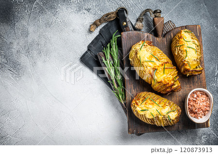 Roasted hasselback potatoes with cheese, garlic, thyme and rosemary. White background. Top view. Copy space 120873913