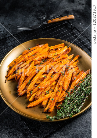 Baked sweet potato fries on a plate with herbs. Black background. Top view Baked sweet potato fries on a plate with herbs. Black background. Top view 120873917