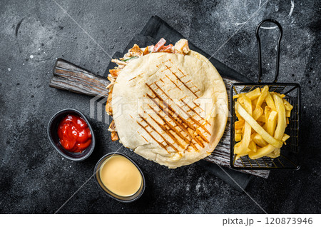 Turkish doner kebab in grilled pita bread with chicken meat. Black background. Top view Turkish doner kebab in grilled pita bread with chicken meat. Black background. Top view 120873946