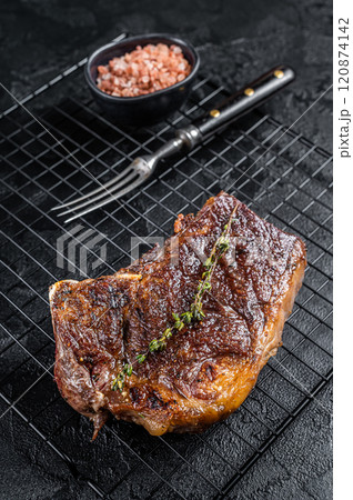 Grilled Striploin beef meat steak or new york steak on a grill rack. Black background. Top view 120874142