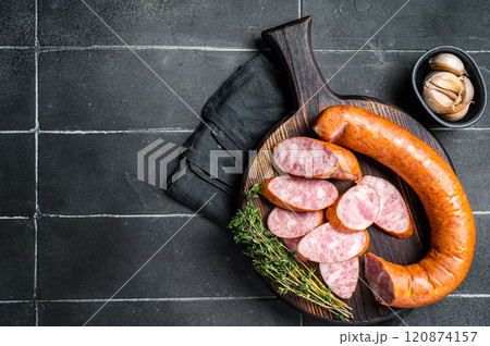 Sliced Krakow Smoked sausage on a wooden board. Black background. Top view. COpy space Sliced Krakow Smoked sausage on a wooden board. Black background. Top view. COpy space 120874157