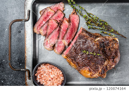 Grilled Wagyu Striploin beef meat steak or new york steak in a steel tray. Black background. Top view 120874164