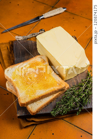 Spreading butter on toast with knife . Orange background. Top view 120874175