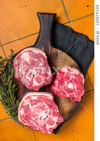 Raw lamb neck chops, fresh mutton meat on a butcher board with herbs. Orange background. Top view 120874188