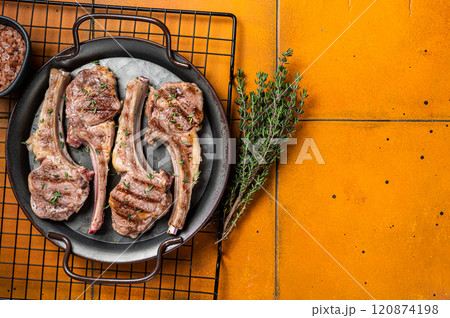 BBQ with Grilled lamb meat chops, mutton steaks with herbs. Orange background. Top view. Copy space 120874198
