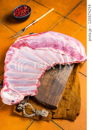 Raw rack of lamb mutton ribs on butcher board with spices. Orange background. Top view Raw rack of lamb mutton ribs on butcher board with spices. Orange background. Top view 120874254