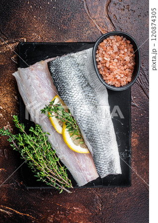 Sea Bass fillets, Raw Seabass fish with thyme, pink salt and lemon on marble board. Dark background. Top view 120874305