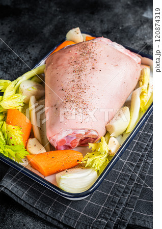 Cooking of Schweinshaxe from Raw pork shank knuckle with vegetables and herbs. Black background. Top view 120874319