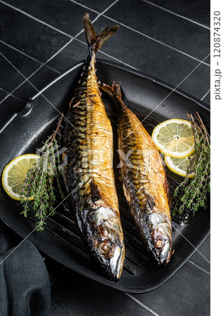 Grilled mackerel fish with lemon, herbs and spices in a skillet. Black background. Top view 120874320
