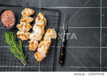 Chicken shish kebab, grilled skewers with herbs and spices on a rack. Black background. Top view. Copy space Chicken shish kebab, grilled skewers with herbs and spices on a rack. Black background. Top view. Copy space 120874339