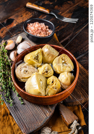Appetizer Artichoke hearts pickled in olive oil with herbs and spices Wooden background. Top view 120874369