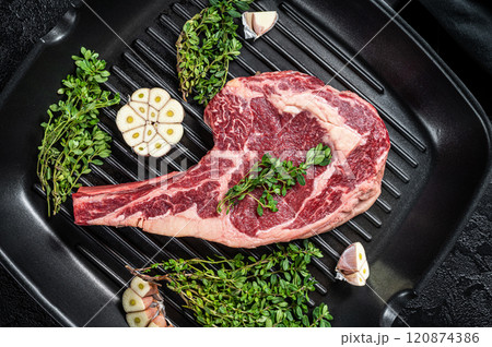 Ready for cooking Raw cowboy or rib eye steak in a grill skillet. Black background. Top view 120874386