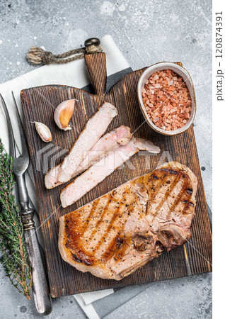 Grilled pork Chop or T-bone meat steak sliced on a wooden board. Gray background. Top view Grilled pork Chop or T-bone meat steak sliced on a wooden board. Gray background. Top view 120874391