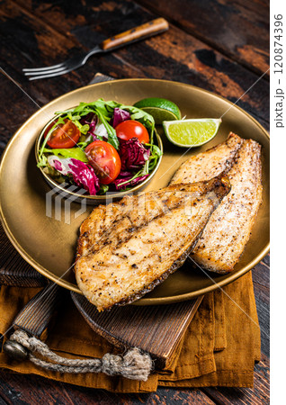 Roasted Gilthead Sea Bream fillets served with fresh vegetable salad. Wooden background. Top view Roasted Gilthead Sea Bream fillets served with fresh vegetable salad. Wooden background. Top view 120874396