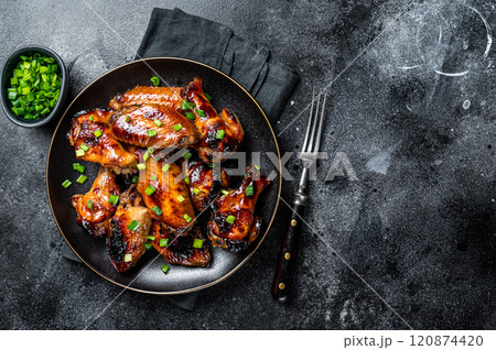 Baked chicken wings with sweet chili sauce in a plate. Black background. Top view. Copy space Baked chicken wings with sweet chili sauce in a plate. Black background. Top view. Copy space 120874420