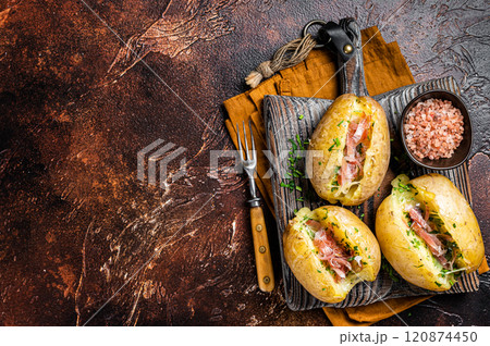 Jacket potatoes baked with cheese, herbs and butter. Dark background. Top view. Copy space Jacket potatoes baked with cheese, herbs and butter. Dark background. Top view. Copy space 120874450