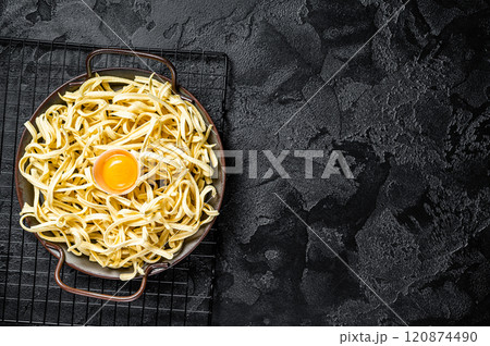 Dry spaetzle egg noodle in a steel tray. Black background. Top view. Copy space Dry spaetzle egg noodle in a steel tray. Black background. Top view. Copy space 120874490