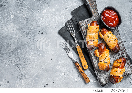 Sausage rolls, Pigs in Blanket puff pastry on wooden board. Gray background. Top view. Copy space Sausage rolls, Pigs in Blanket puff pastry on wooden board. Gray background. Top view. Copy space 120874506