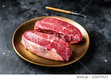 Raw Shoulder Top Blade beef meat steaks on a plate. Black background. Top View 120874521