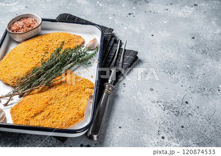 Cooking raw chicken schnitzel in breadcrumbs, uncooked meat steak. Gray background. Top view. Copy space Cooking raw chicken schnitzel in breadcrumbs, uncooked meat steak. Gray background. Top view. Copy space 120874533