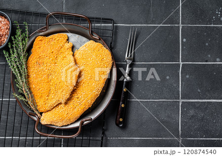 Homemade raw breaded German Weiner Schnitzel. Black background. Top view. Copy space 120874540