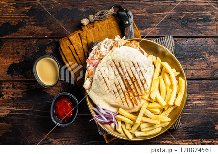 Doner kebab, Shawarma in grilled pita bread with vegetables, meat and french fry. Wooden background. Top view Doner kebab, Shawarma in grilled pita bread with vegetables, meat and french fry. Wooden background. Top view 120874561