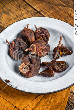 Natural Sun Dried persimmon fruit on a plate. Wooden background. Top view Natural Sun Dried persimmon fruit on a plate. Wooden background. Top view 120874563