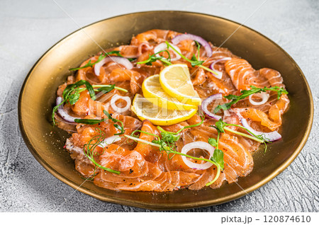 Fresh raw salmon carpaccio slices with onion and arugula served on a plate. White background. Top view Fresh raw salmon carpaccio slices with onion and arugula served on a plate. White background. Top view 120874610