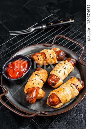 Pigs in Blanket puff pastry sausage wrap roll. Black background. Top view Pigs in Blanket puff pastry sausage wrap roll. Black background. Top view 120874611