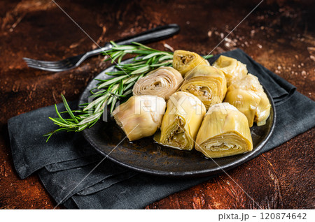 Italian appetizer Artichoke hearts pickled in olive oil with herbs and spices Dark background. Top view Italian appetizer Artichoke hearts pickled in olive oil with herbs and spices Dark background. Top view 120874642