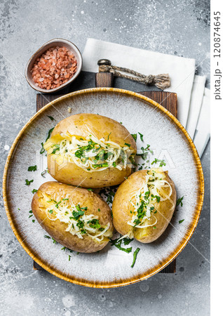 Baked Jacket potatoes with cheese and butter. Gray background. Top view Baked Jacket potatoes with cheese and butter. Gray background. Top view 120874645
