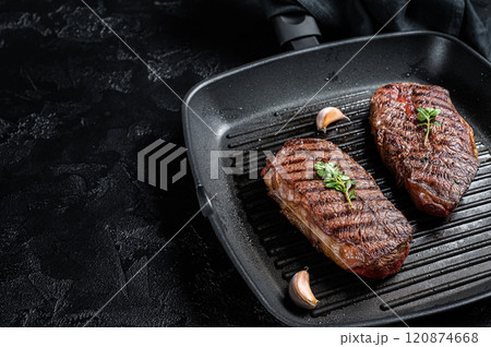 Grilled Top Blade or flat iron roast beef meat steaks on a skillet. Black background. Top View. Copy space Grilled Top Blade or flat iron roast beef meat steaks on a skillet. Black background. Top View. Copy space 120874668